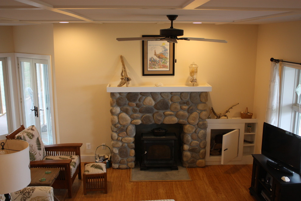 This is an example of a mid-sized country formal enclosed living room in Other with yellow walls, medium hardwood floors, a wood stove, a stone fireplace surround, a freestanding tv and brown floor.