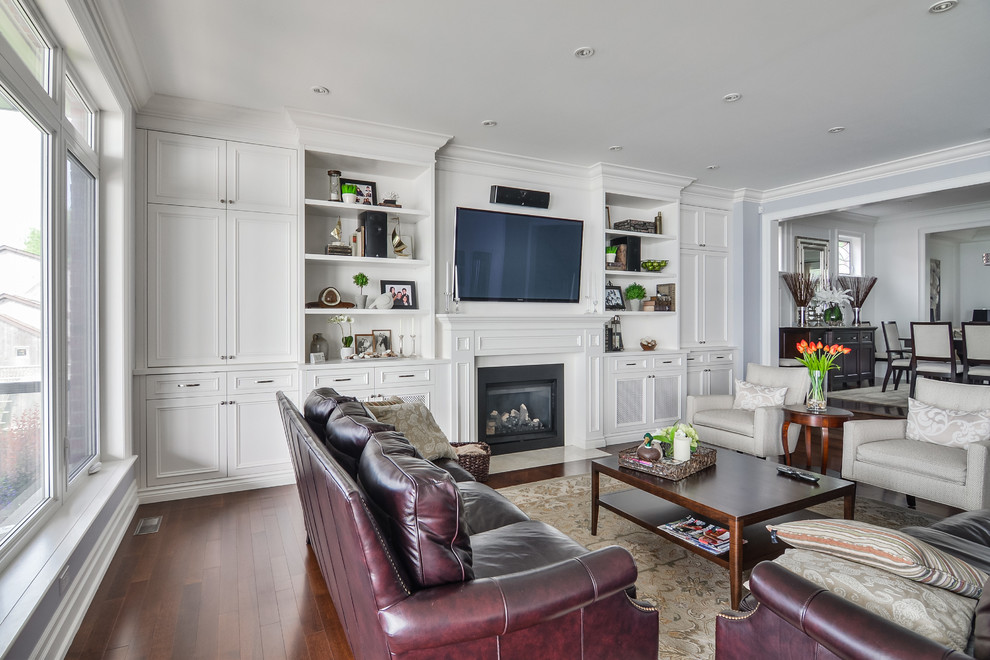 Inspiration for a large traditional open concept living room in Toronto with white walls, dark hardwood floors, a standard fireplace and a wall-mounted tv.