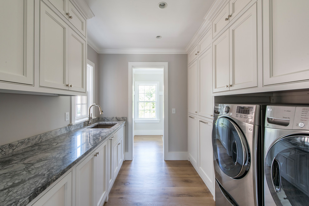 Photo of an expansive beach style galley dedicated laundry room in Boston with an undermount sink, white cabinets, granite benchtops, a side-by-side washer and dryer and beaded inset cabinets.