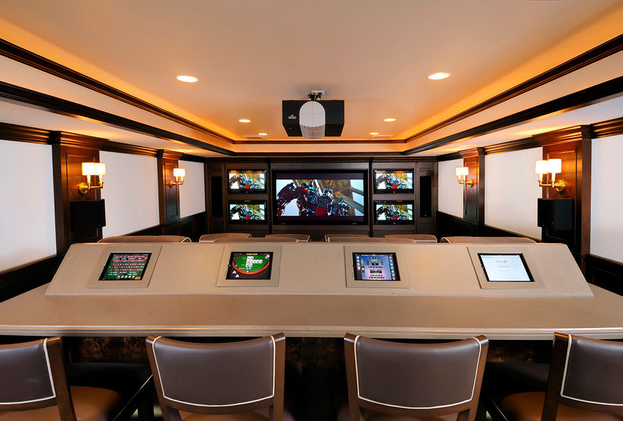 This is an example of a large modern enclosed home theatre in San Diego with multi-coloured walls, carpet and a projector screen.
