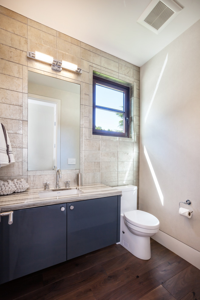 This is an example of a mid-sized contemporary powder room in San Francisco with a two-piece toilet, beige tile, porcelain tile, beige walls, dark hardwood floors, an undermount sink, brown floor, flat-panel cabinets, black cabinets and quartzite benchtops.