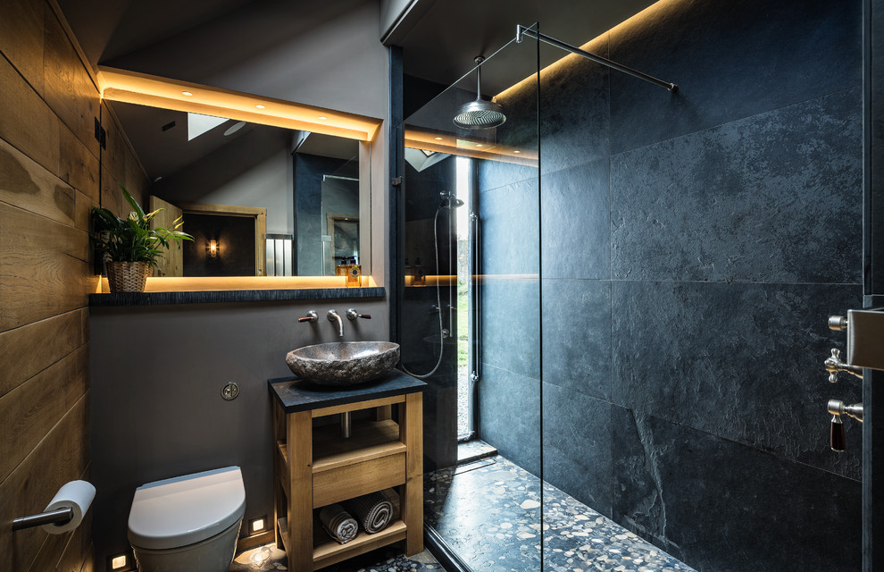 Beach style 3/4 bathroom in Cheshire with open cabinets, light wood cabinets, an alcove shower, a wall-mount toilet, black tile, black walls, a vessel sink and an open shower.