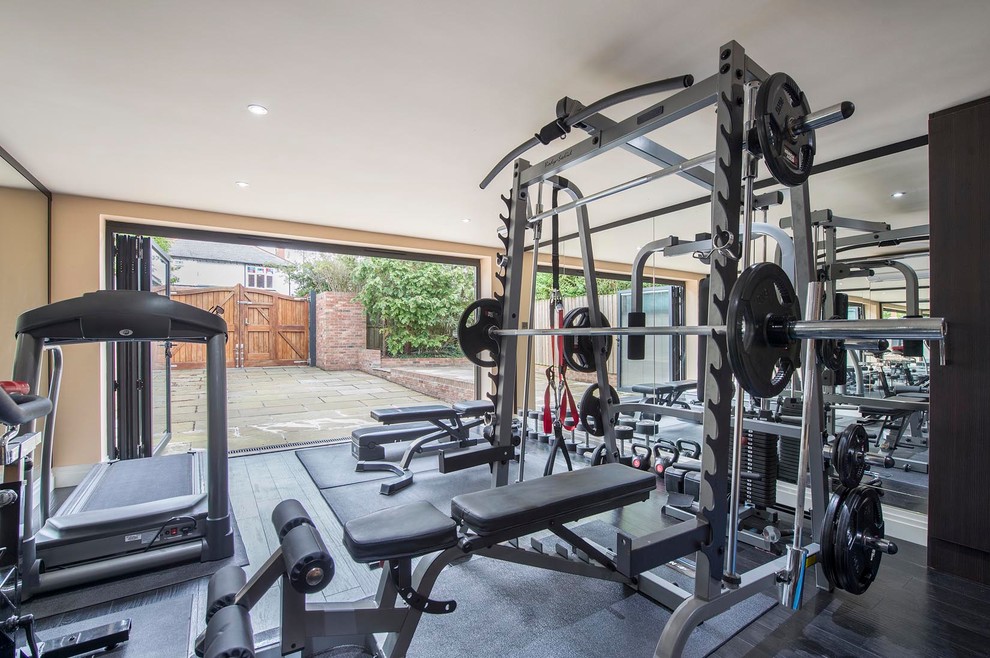 This is an example of a mid-sized contemporary home weight room in Other with beige walls, dark hardwood floors and black floor.