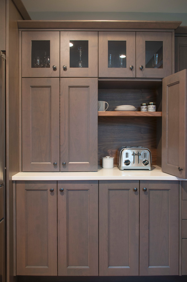 Inspiration for a mid-sized transitional galley medium tone wood floor and brown floor eat-in kitchen remodel in Burlington with a farmhouse sink, flat-panel cabinets, gray cabinets, quartz countertops, white backsplash, subway tile backsplash, stainless steel appliances and a peninsula