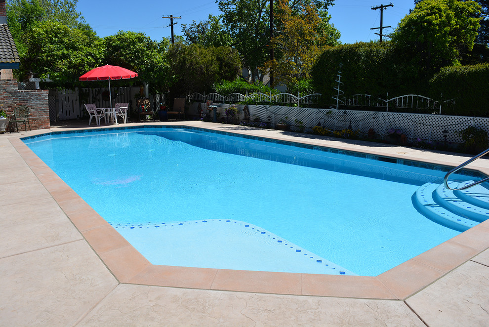 Inspiration for a large traditional side yard custom-shaped pool in Sacramento with stamped concrete.