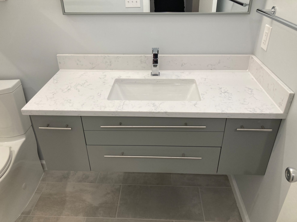 Photo of a mid-sized modern master bathroom in DC Metro with flat-panel cabinets, grey cabinets, an alcove tub, an alcove shower, a two-piece toilet, white tile, porcelain tile, grey walls, porcelain floors, an undermount sink, quartzite benchtops, grey floor, a shower curtain, white benchtops, a single vanity and a floating vanity.