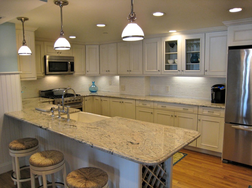Mid-sized transitional u-shaped medium tone wood floor and brown floor open concept kitchen photo in Providence with a farmhouse sink, recessed-panel cabinets, white cabinets, granite countertops, white backsplash, ceramic backsplash, stainless steel appliances, a peninsula and gray countertops