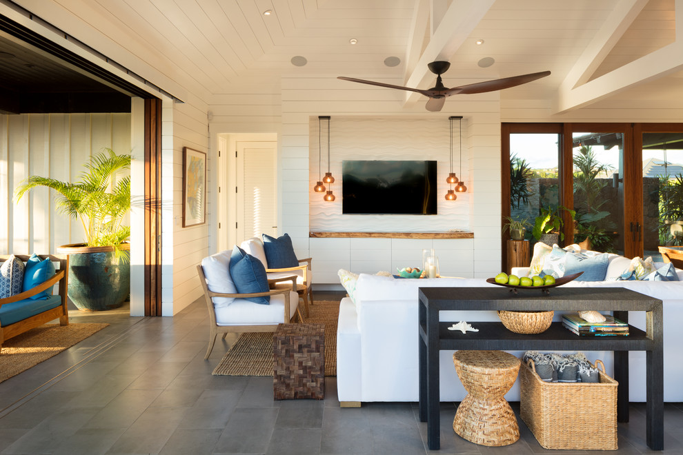 This is an example of a mid-sized tropical open concept living room in Hawaii with white walls, ceramic floors, no fireplace, a built-in media wall and grey floor.