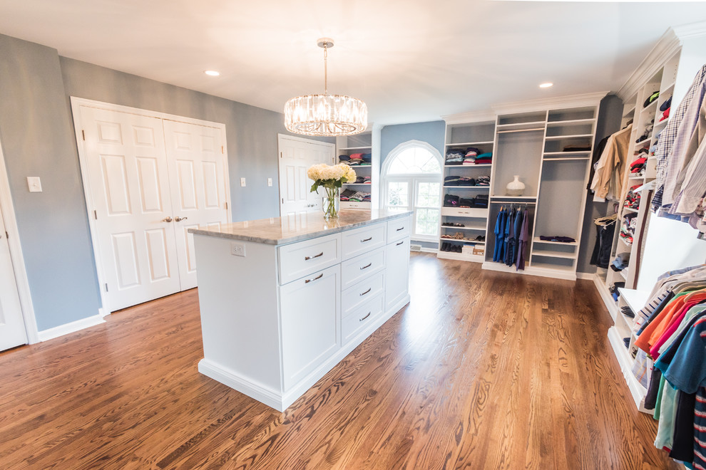 Design ideas for a large traditional gender-neutral dressing room in Philadelphia with medium hardwood floors, brown floor, shaker cabinets and white cabinets.