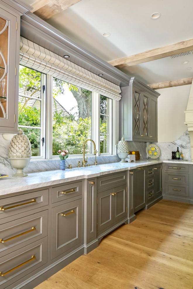 Inspiration for an expansive mediterranean u-shaped kitchen in Los Angeles with an undermount sink, grey cabinets, marble benchtops, white splashback, marble splashback, panelled appliances, light hardwood floors, with island, beige floor, white benchtop and recessed-panel cabinets.