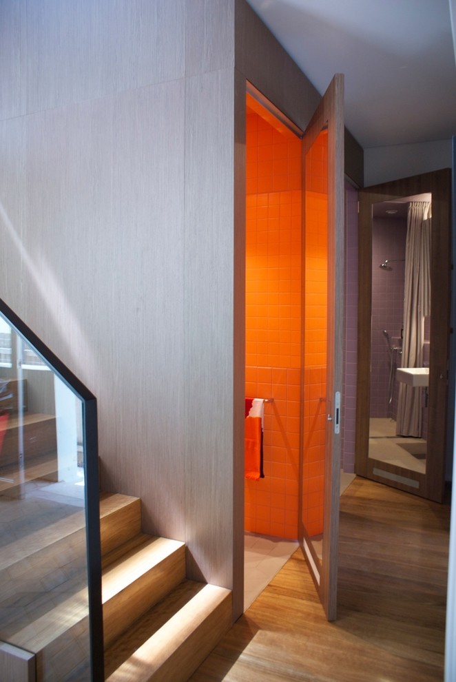 Photo of a small contemporary powder room in Sydney with a wall-mount sink, a two-piece toilet, orange tile, ceramic tile, orange walls and porcelain floors.