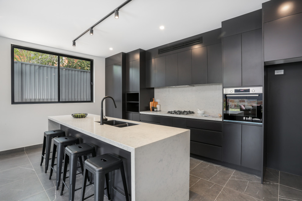Inspiration for a large modern single-wall open plan kitchen in Sydney with an undermount sink, flat-panel cabinets, black cabinets, quartz benchtops, white splashback, engineered quartz splashback, black appliances, ceramic floors, with island, grey floor, white benchtop and timber.