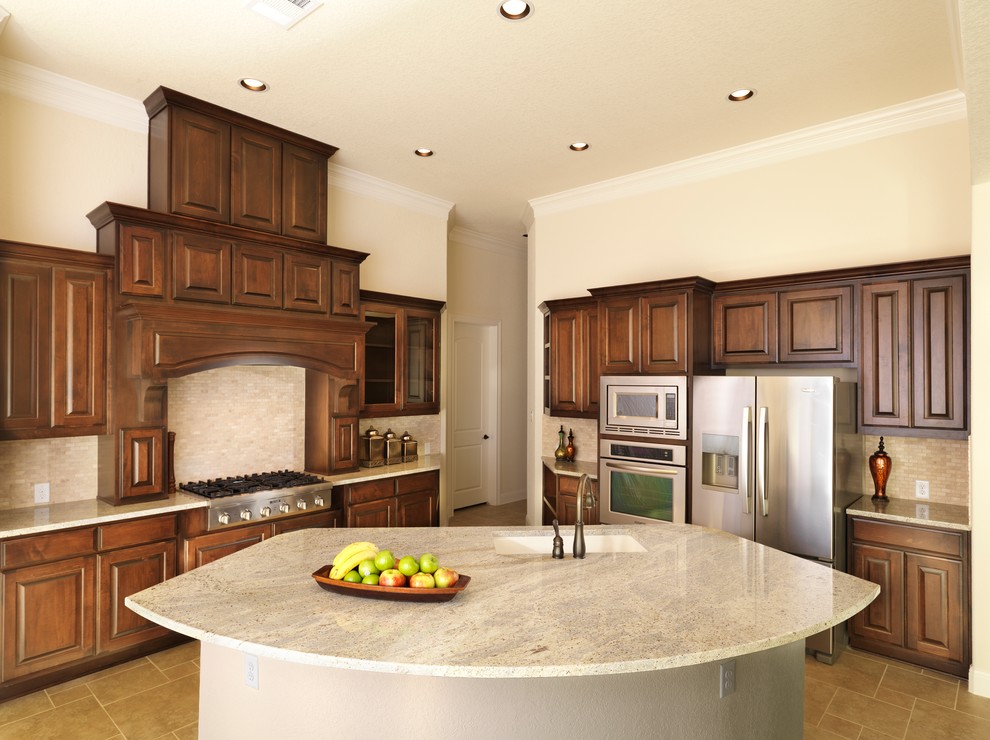 Inspiration for a traditional l-shaped kitchen in Austin with granite benchtops, stainless steel appliances, raised-panel cabinets, dark wood cabinets and beige splashback.