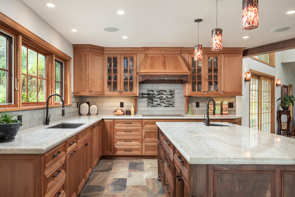 Photo of a large traditional eat-in kitchen in Sacramento with an undermount sink, raised-panel cabinets, medium wood cabinets, granite benchtops, grey splashback, glass tile splashback, panelled appliances, slate floors, with island, multi-coloured floor and beige benchtop.