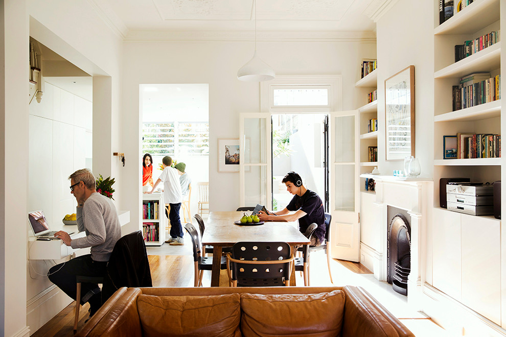 Contemporary open plan dining in Sydney with white walls, medium hardwood floors and a standard fireplace.