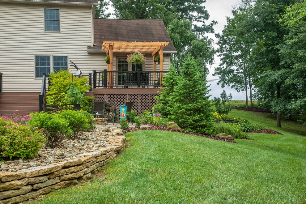 Photo of a mid-sized transitional drought-tolerant and full sun backyard stone retaining wall landscape for summer.