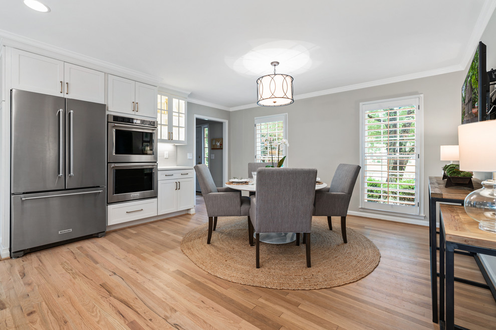 Inspiration for a transitional light wood floor and brown floor eat-in kitchen remodel in Atlanta with an undermount sink, shaker cabinets, white cabinets, quartz countertops, gray backsplash, ceramic backsplash, stainless steel appliances, an island and white countertops