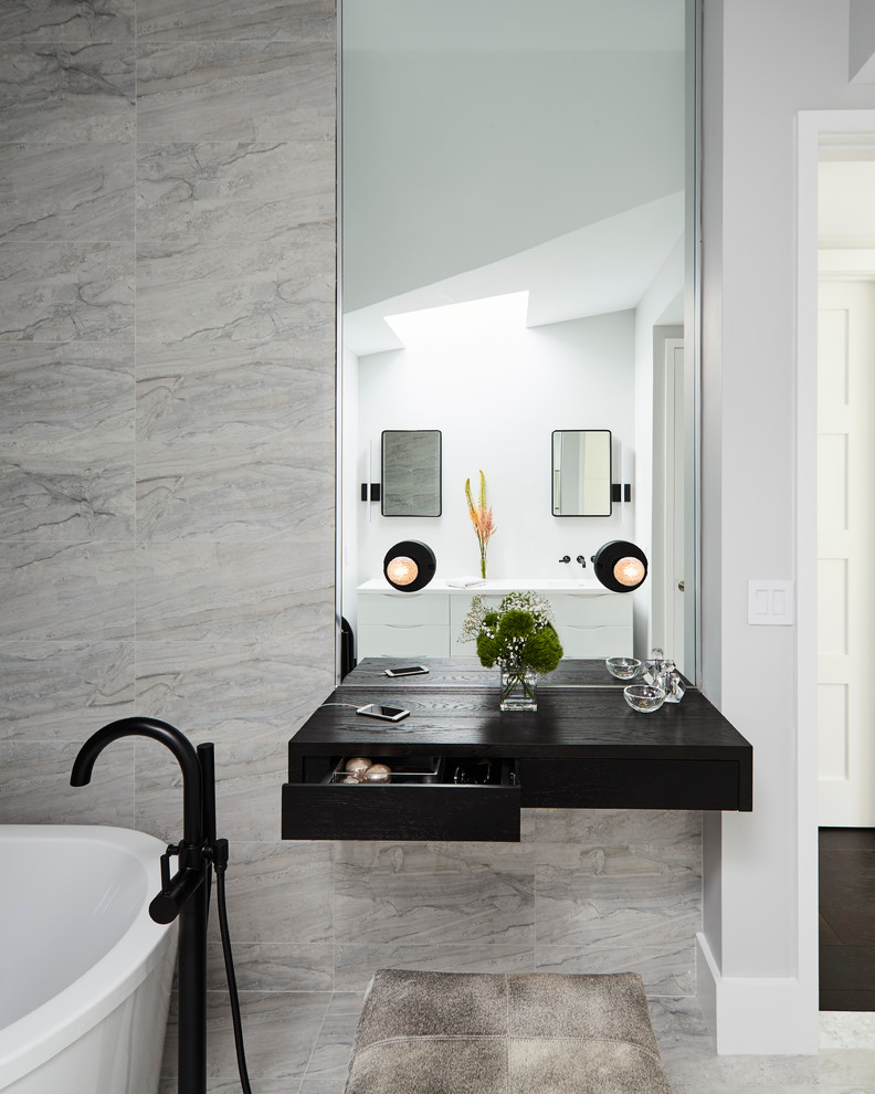 Design ideas for a contemporary master bathroom in New York with a freestanding tub, gray tile, porcelain tile, porcelain floors, flat-panel cabinets and dark wood cabinets.