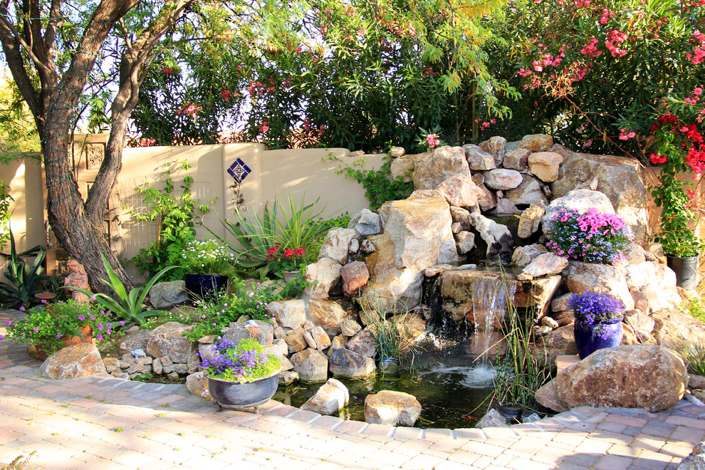 Photo of a mid-sized mediterranean backyard partial sun xeriscape for spring in Phoenix with with pond and brick pavers.