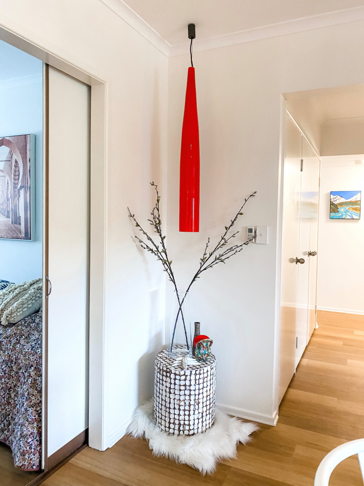 This is an example of a small beach style hallway in Sunshine Coast with white walls, medium hardwood floors and brown floor.