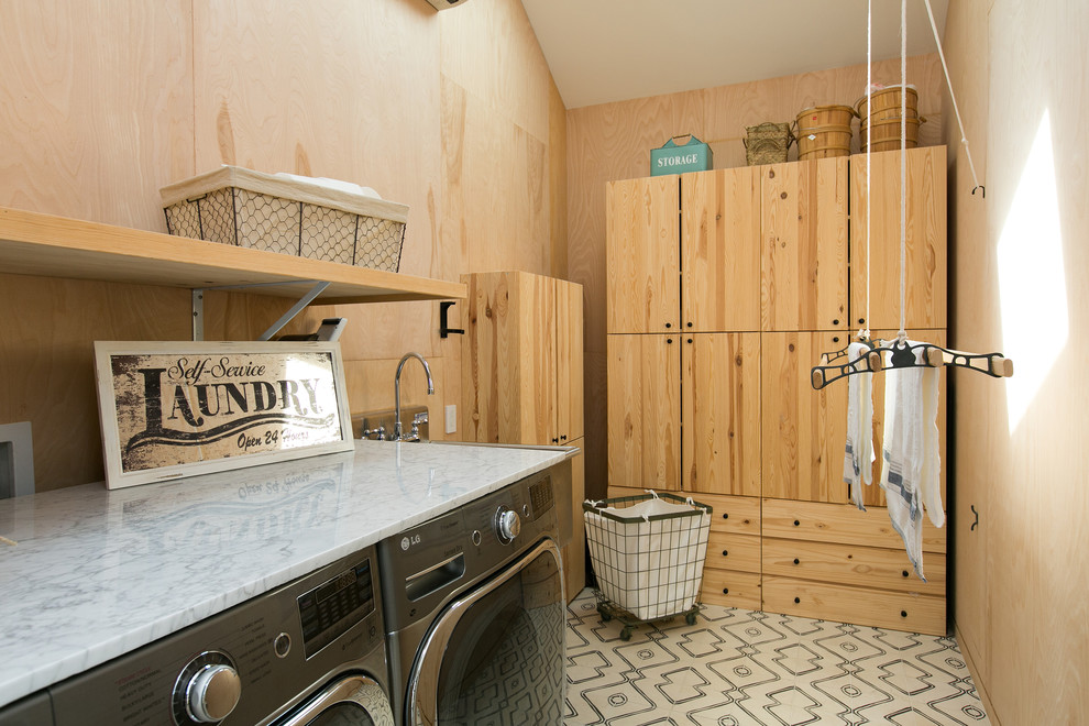 Inspiration for a country l-shaped dedicated laundry room in Los Angeles with an utility sink, flat-panel cabinets, medium wood cabinets, brown walls, a side-by-side washer and dryer, white floor and white benchtop.
