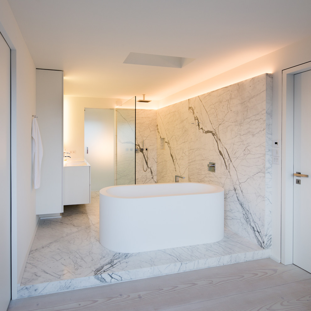 Photo of a mid-sized contemporary bathroom in Berlin with white cabinets, a freestanding tub, a curbless shower, white tile, white walls, stone slab and marble floors.