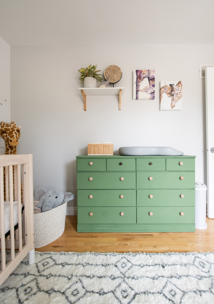 Small eclectic gender neutral nursery in Denver with beige walls, light hardwood flooring and wallpapered walls.