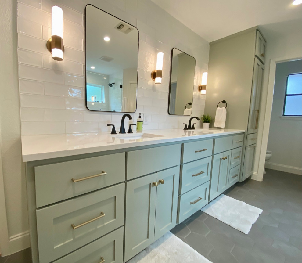Inspiration for a mid-sized traditional master bathroom in Austin with flat-panel cabinets, green cabinets, an alcove shower, white tile, subway tile, white walls, porcelain floors, an integrated sink, solid surface benchtops, grey floor, a hinged shower door, white benchtops, an enclosed toilet, a double vanity, a built-in vanity, wood and wood walls.
