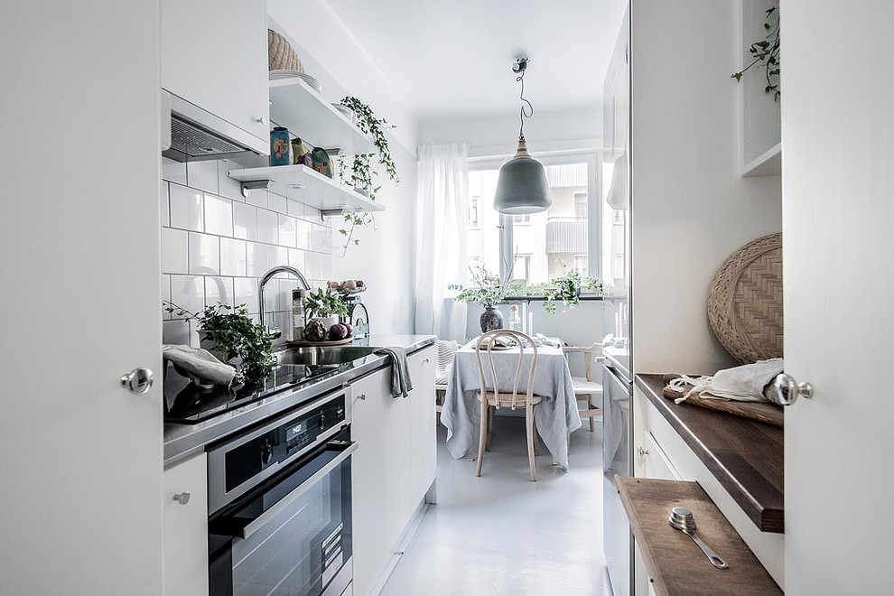 Design ideas for a small scandinavian galley eat-in kitchen in Stockholm with flat-panel cabinets, white cabinets, wood benchtops, white splashback and no island.