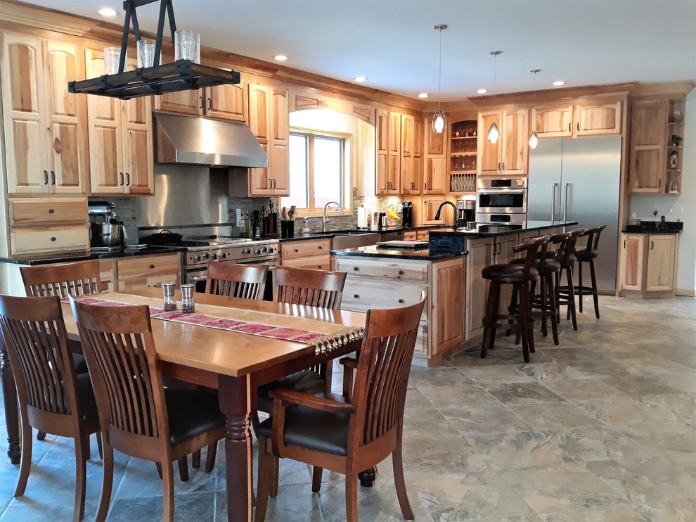 This is an example of an expansive country u-shaped eat-in kitchen in Boston with raised-panel cabinets, light wood cabinets, marble benchtops, with island, green benchtop, a farmhouse sink, beige splashback, ceramic splashback, stainless steel appliances, porcelain floors and beige floor.