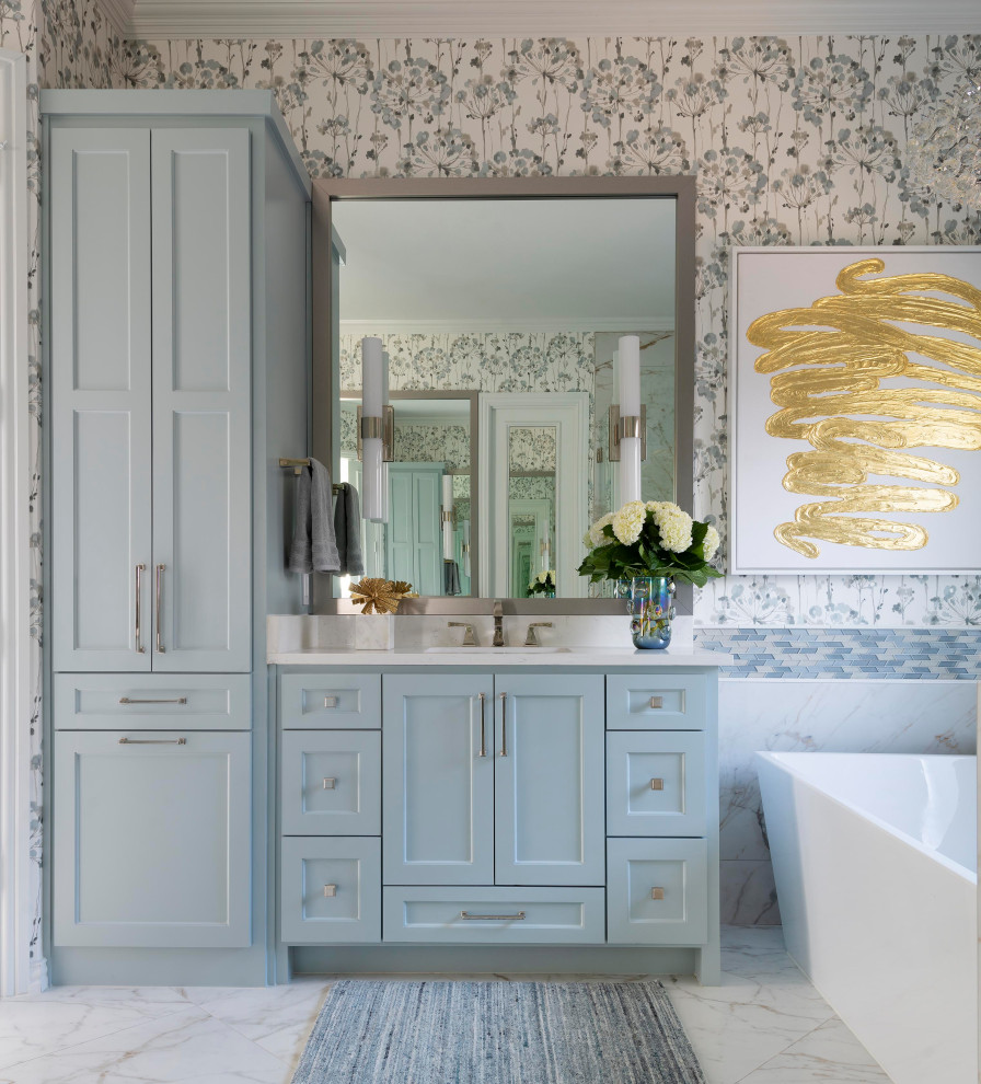 Inspiration for a transitional master bathroom in Dallas with blue cabinets, a freestanding tub, a one-piece toilet, blue tile, multi-coloured walls, an undermount sink, white floor, white benchtops, a double vanity, a built-in vanity and wallpaper.