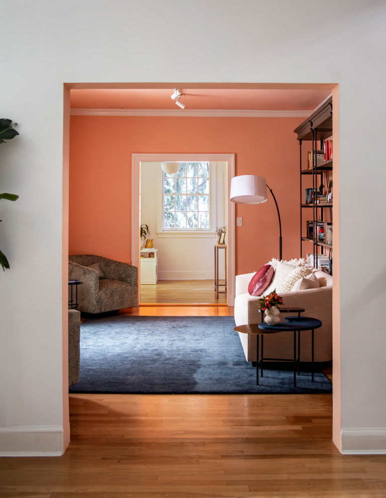 Photo of a transitional enclosed living room in New York with orange walls, medium hardwood floors and brown floor.