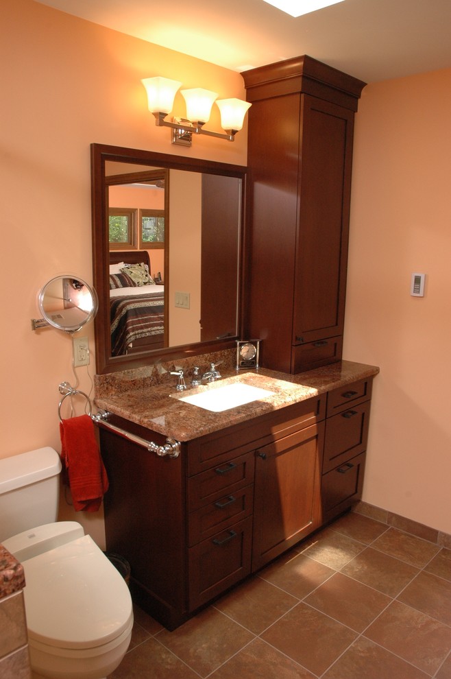 This is an example of a mid-sized traditional master bathroom in Cincinnati with furniture-like cabinets, dark wood cabinets, a curbless shower, a two-piece toilet, beige tile, brown tile, multi-coloured tile, ceramic tile, orange walls, ceramic floors, an undermount sink, granite benchtops, brown floor and an open shower.