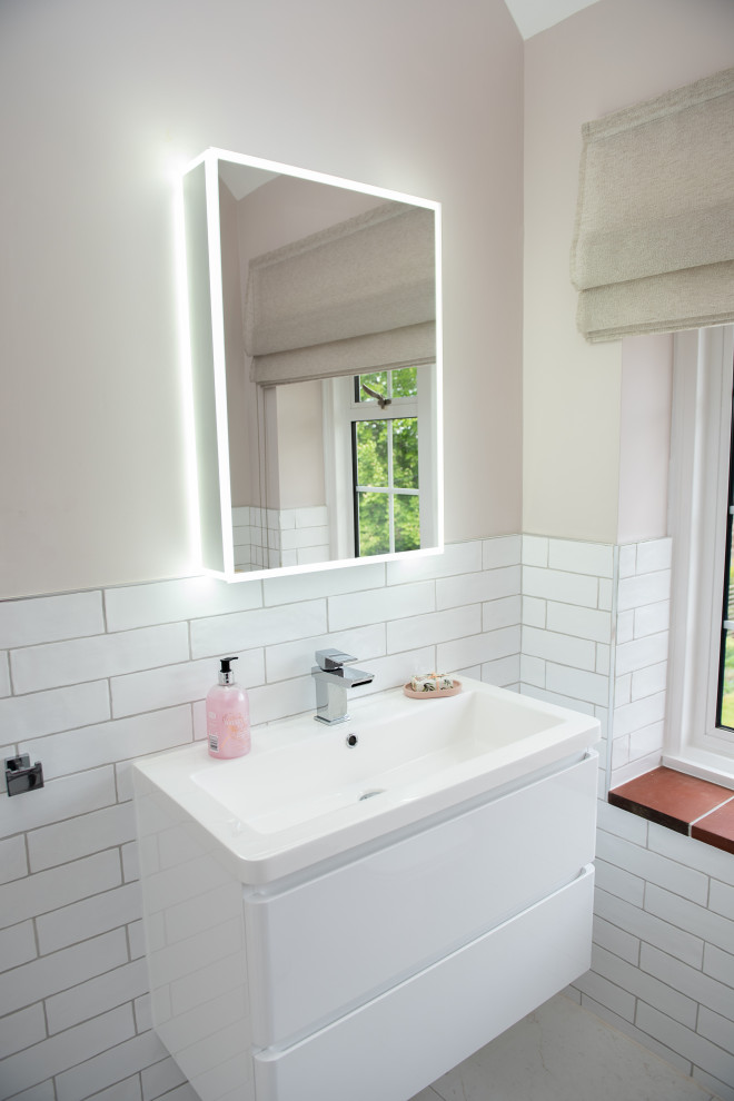 На фото: маленькая главная ванная комната в современном стиле с белыми фасадами, душем без бортиков, белой плиткой, керамической плиткой, розовыми стенами, полом из цементной плитки, накладной раковиной, бежевым полом, душем с распашными дверями, тумбой под одну раковину, встроенной тумбой и потолком с обоями для на участке и в саду