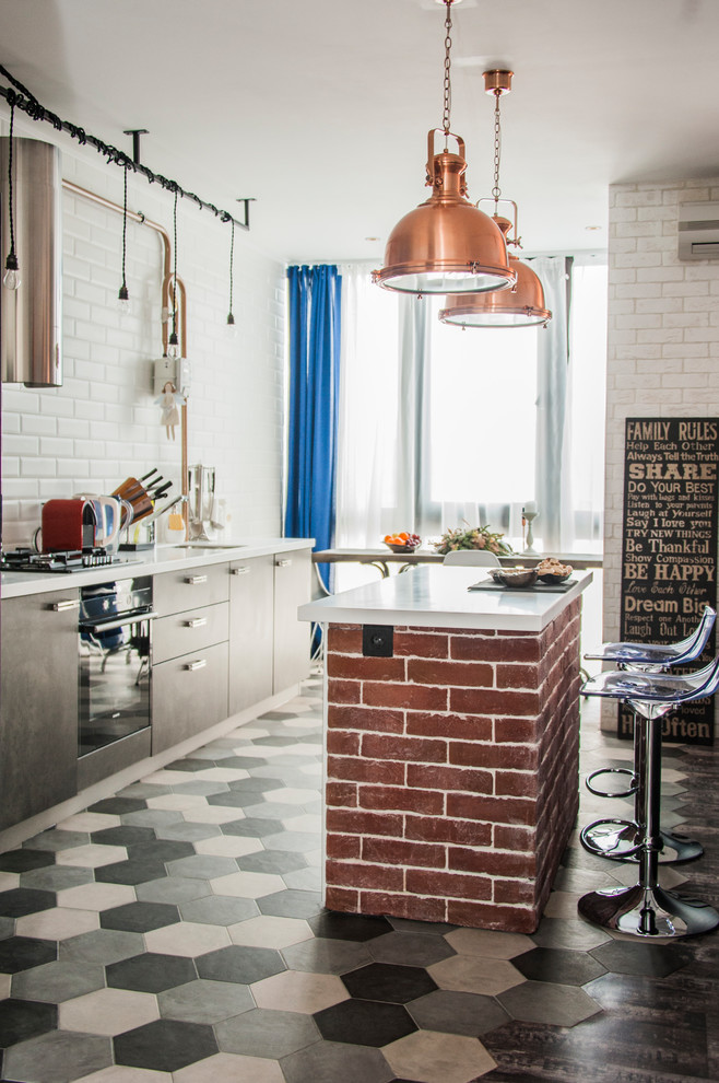 Inspiration for a small industrial single-wall kitchen in Moscow with an undermount sink, flat-panel cabinets, grey cabinets, solid surface benchtops, white splashback, subway tile splashback, black appliances, porcelain floors, with island, white benchtop and multi-coloured floor.
