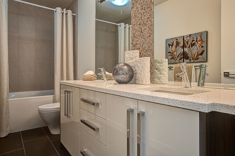 This is an example of a small modern kids bathroom in Vancouver with an undermount sink, flat-panel cabinets, white cabinets, quartzite benchtops, an alcove tub, a shower/bathtub combo, a two-piece toilet, multi-coloured tile, ceramic tile, white walls and ceramic floors.