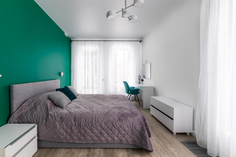 Пример оригинального дизайна: большая гостевая спальня (комната для гостей) в стиле модернизм с зелеными стенами, полом из ламината, коричневым полом и акцентной стеной без камина