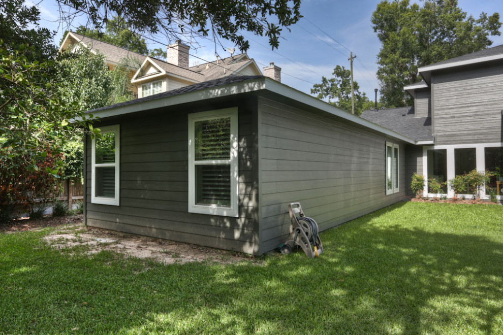 This is an example of a traditional one-storey grey apartment exterior in Houston with concrete fiberboard siding, a shed roof and a shingle roof.