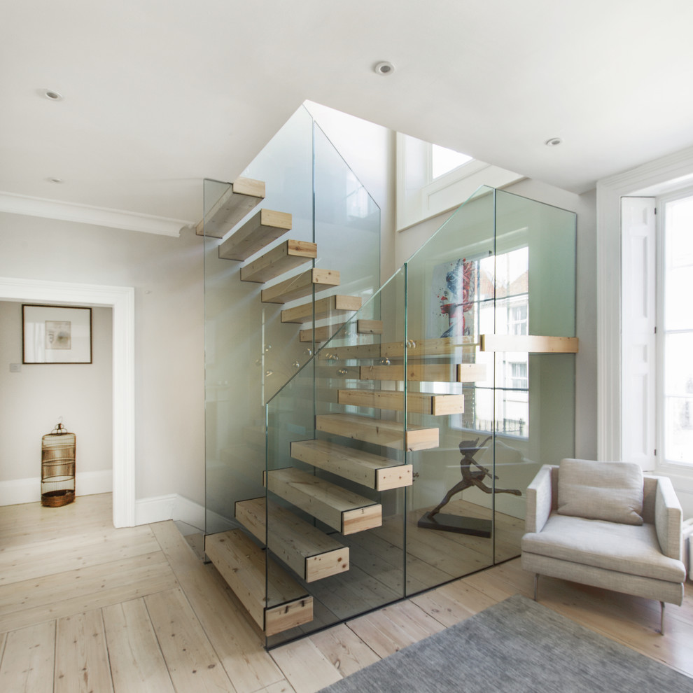 Photo of a contemporary wood floating staircase in Hampshire with open risers and glass railing.