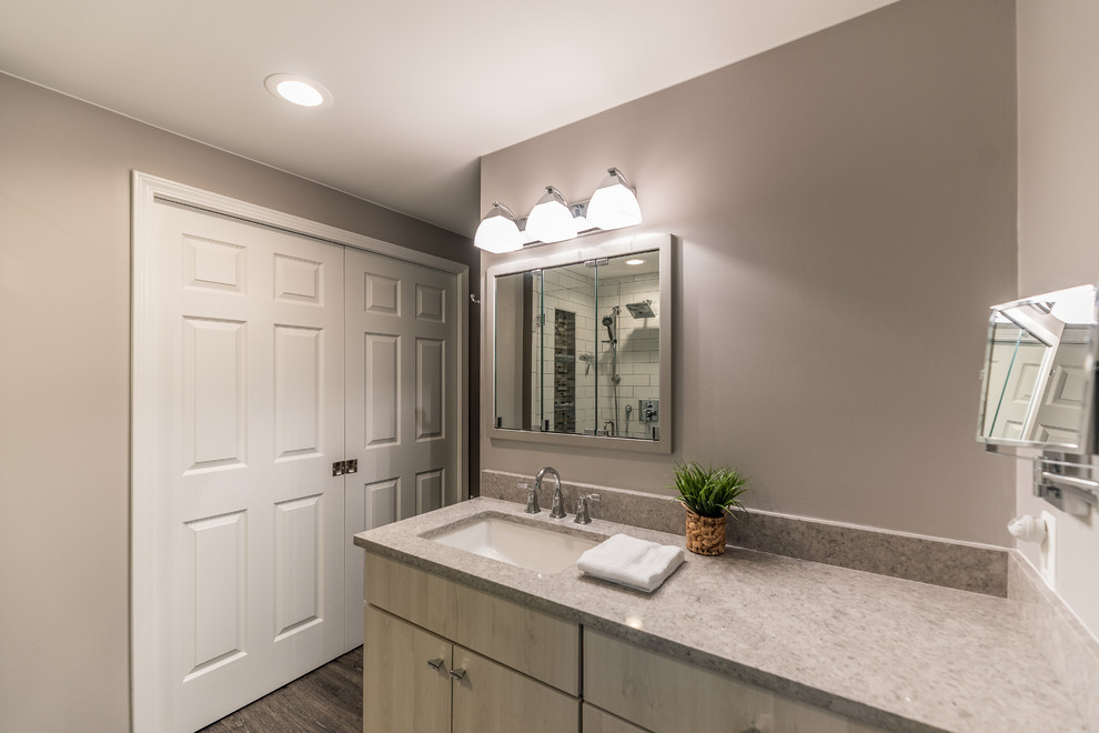 Inspiration for a mid-sized contemporary master bathroom in Detroit with flat-panel cabinets, grey cabinets, a corner shower, a two-piece toilet, white tile, glass sheet wall, grey walls, vinyl floors, an undermount sink, glass benchtops, multi-coloured floor, a hinged shower door and grey benchtops.
