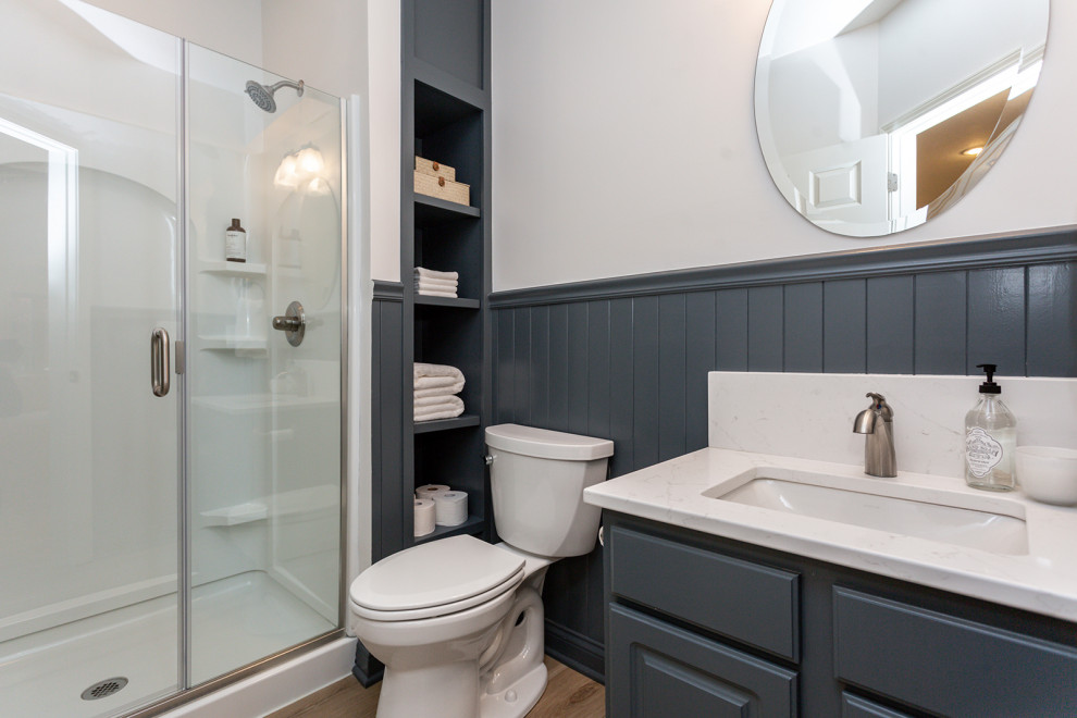 Idéer för stora vintage vitt badrum med dusch, med luckor med upphöjd panel, grå skåp, en dusch i en alkov, en toalettstol med separat cisternkåpa, vita väggar, ljust trägolv, ett undermonterad handfat, bänkskiva i kvarts, brunt golv och dusch med gångjärnsdörr