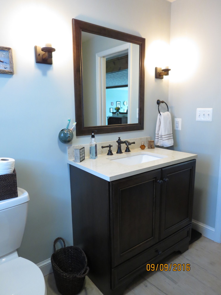 Inspiration for a mid-sized beach style 3/4 bathroom in DC Metro with recessed-panel cabinets, dark wood cabinets, an alcove tub, an alcove shower, porcelain tile, blue walls, porcelain floors, an integrated sink and solid surface benchtops.