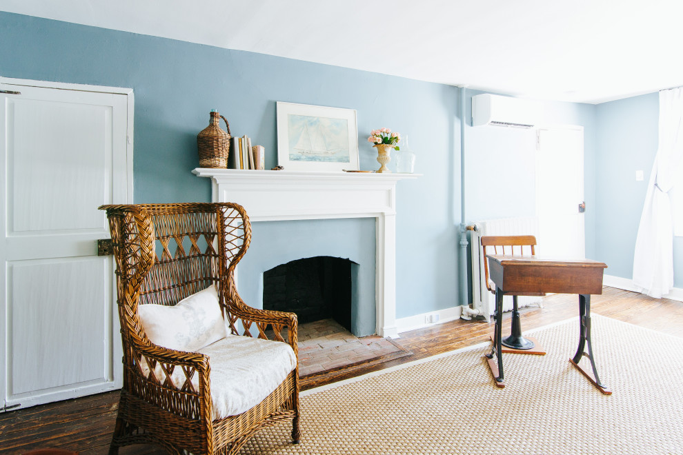 Ejemplo de dormitorio principal clásico grande con paredes azules, suelo de madera en tonos medios, todas las chimeneas, marco de chimenea de yeso, suelo marrón y vigas vistas