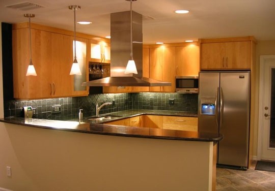 Mid-sized transitional u-shaped ceramic tile kitchen photo in Tampa with a double-bowl sink, flat-panel cabinets, light wood cabinets, granite countertops, green backsplash, ceramic backsplash, stainless steel appliances and a peninsula
