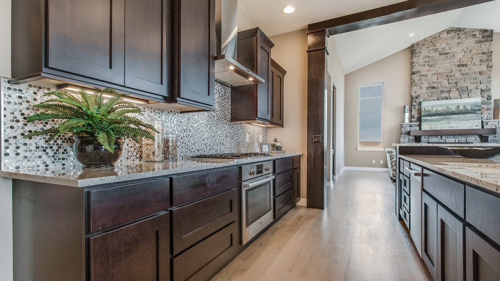 Eat-in kitchen - large transitional l-shaped light wood floor eat-in kitchen idea in Denver with granite countertops, gray backsplash, stainless steel appliances, an island, shaker cabinets, dark wood cabinets and mosaic tile backsplash