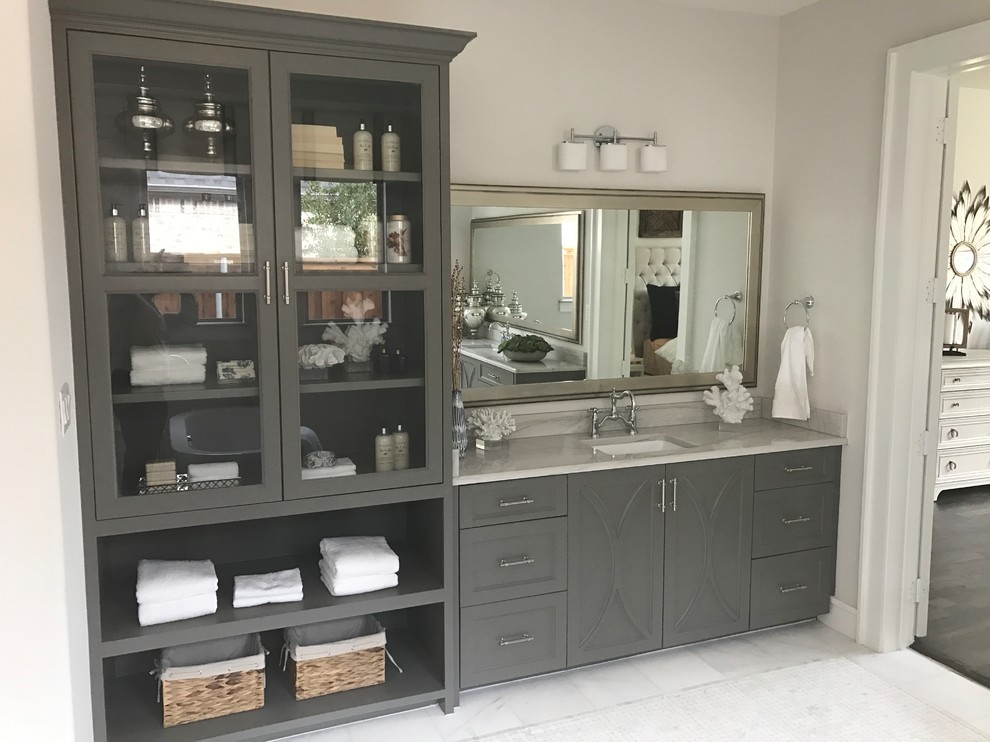 Design ideas for a mid-sized transitional bathroom in Dallas with recessed-panel cabinets, grey cabinets, a corner shower, white tile, grey walls, marble floors, an undermount sink, marble benchtops, grey floor, a hinged shower door and grey benchtops.