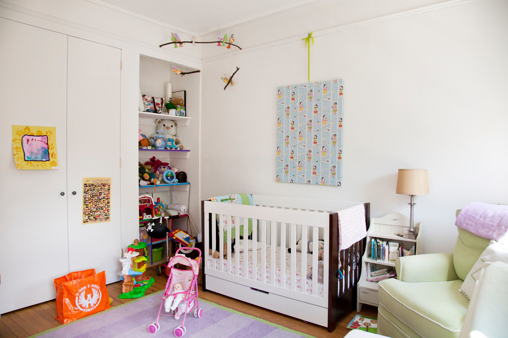 Large contemporary nursery in New York with white walls and medium hardwood floors for girls.