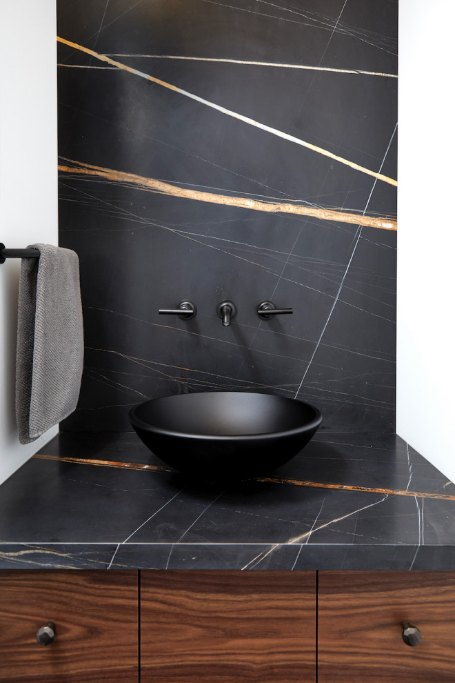 Inspiration for a small contemporary powder room in Toronto with flat-panel cabinets, multi-coloured tile, white walls, a built-in vanity, brown cabinets, a wall-mount toilet, marble, limestone floors, a vessel sink, marble benchtops, black floor, black benchtops and wood.
