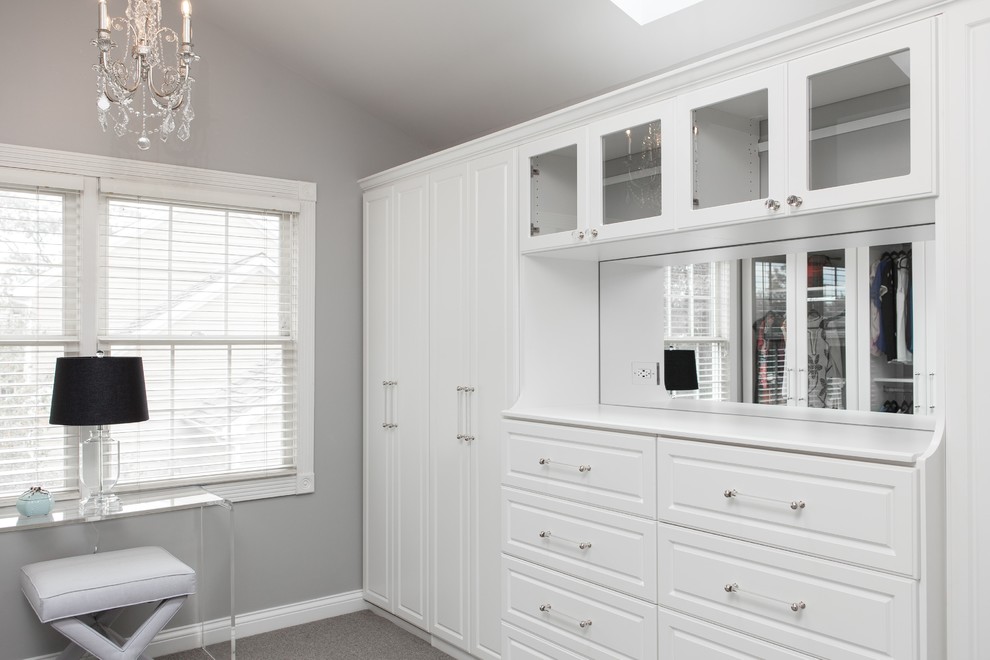 This is an example of a large traditional walk-in wardrobe in Chicago with raised-panel cabinets, white cabinets, carpet and grey floor.