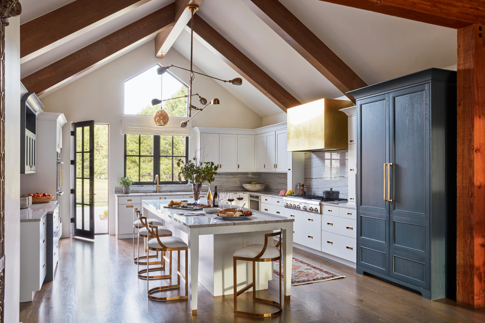Klassische Küche mit Küchenrückwand in Weiß, Elektrogeräten mit Frontblende, braunem Holzboden, Kücheninsel, weißer Arbeitsplatte und freigelegten Dachbalken in Denver